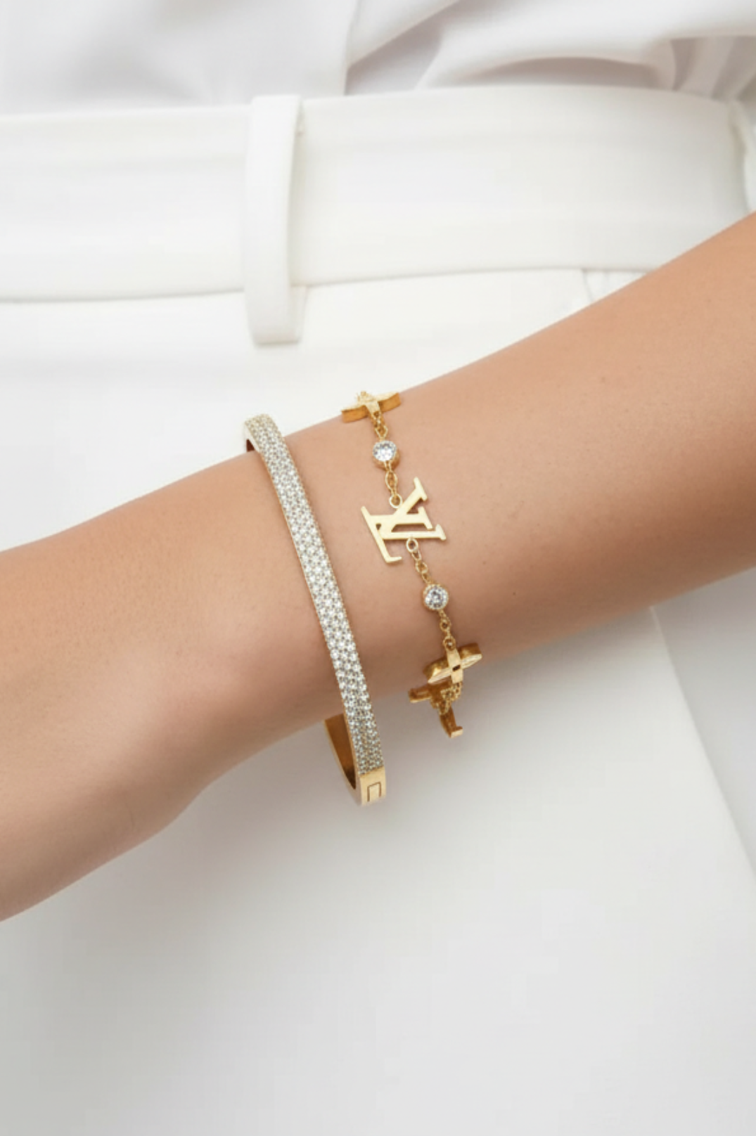 Gold bracelets on a wrist against a white background