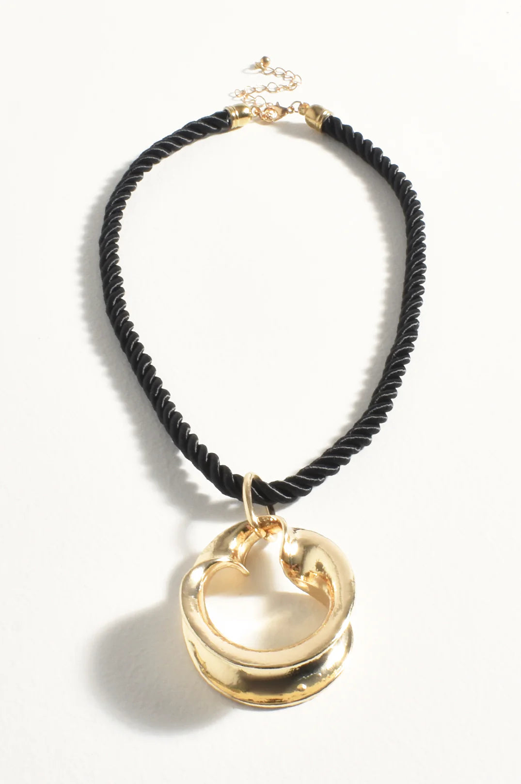 Black cord necklace with gold circular pendant on a white background