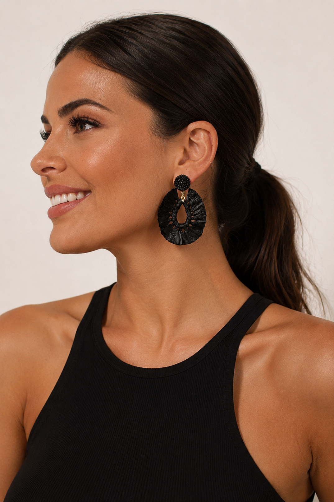 Woman wearing black earrings with a neutral background