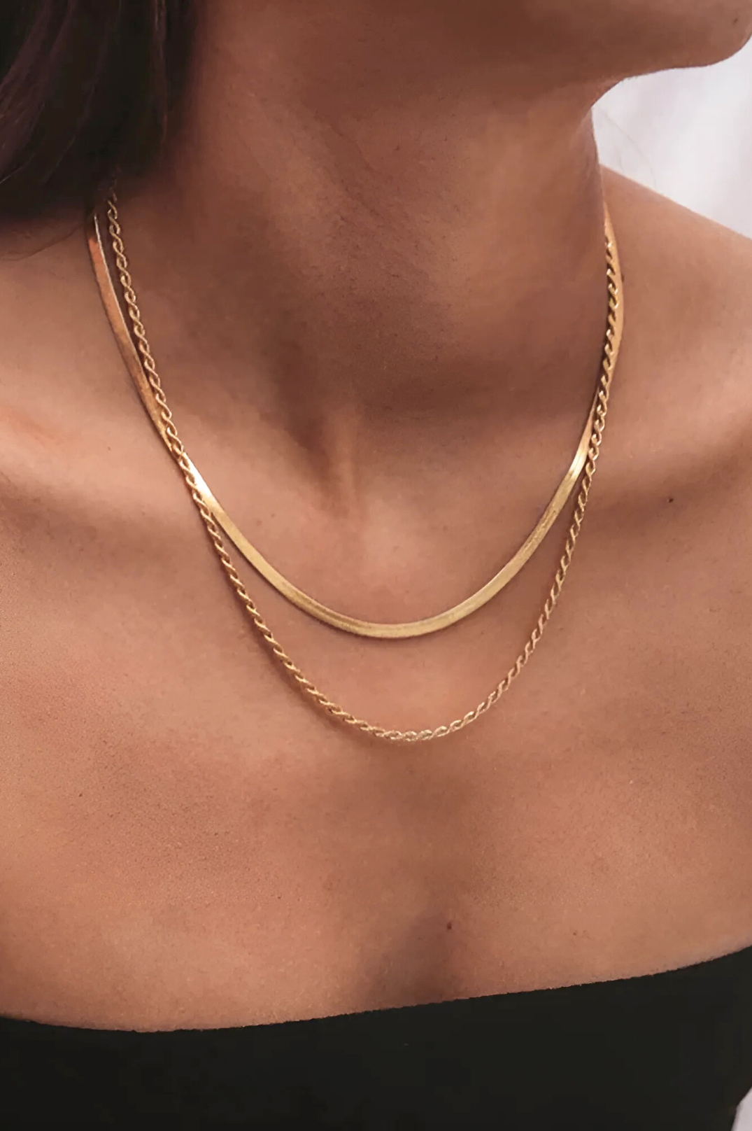 Gold chain necklace on a person's neck with a blurred background