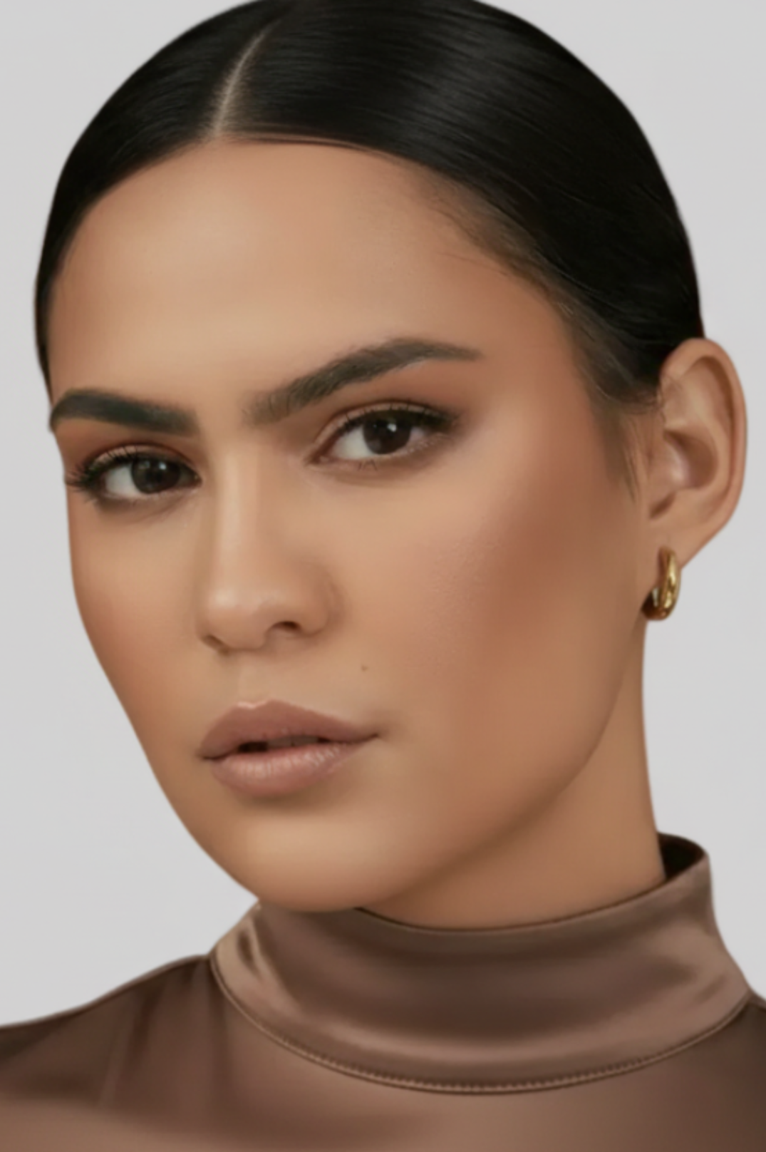 Close-up of a person wearing a brown turtleneck against a neutral background
