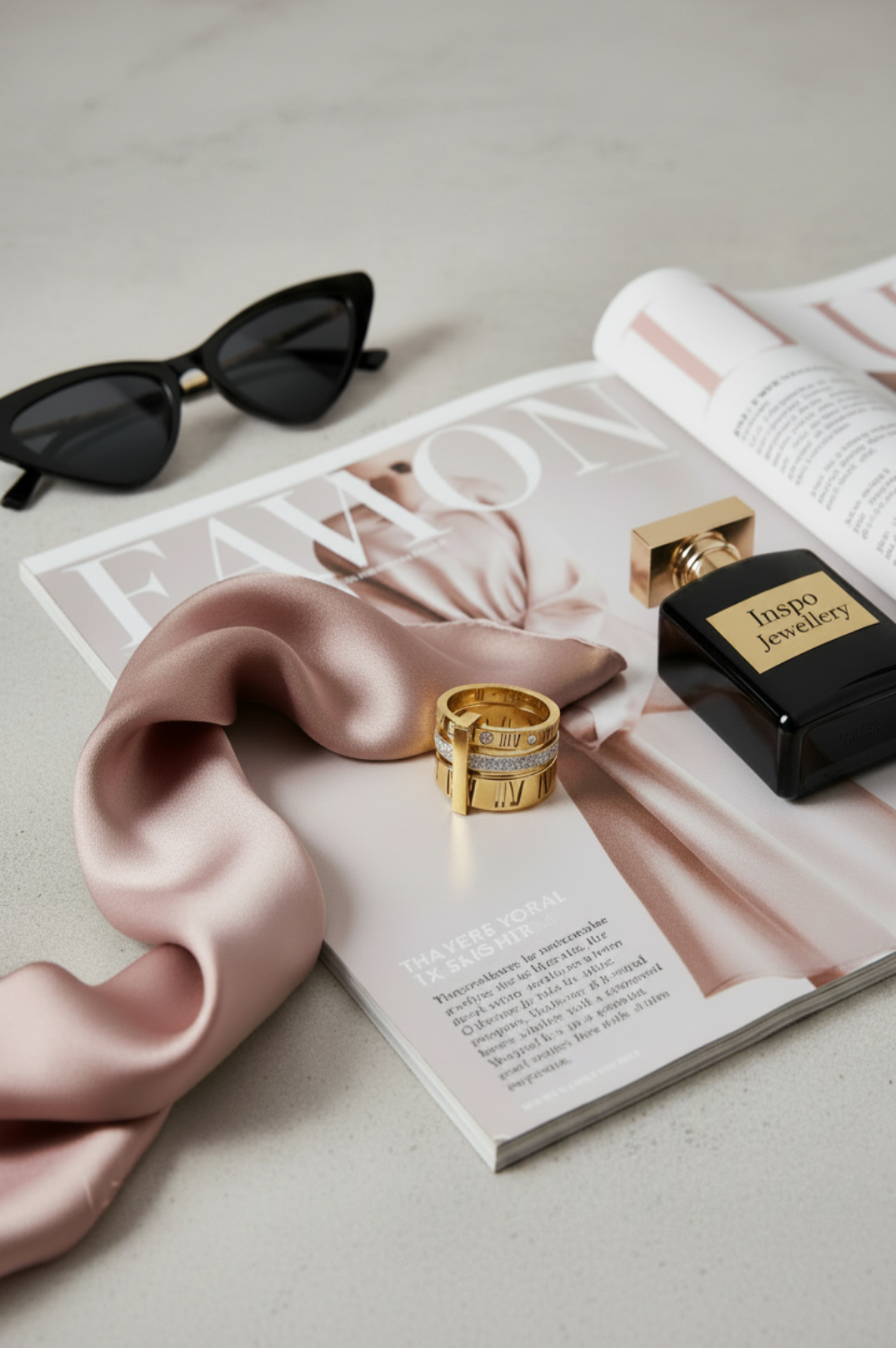 Perfume bottle, sunglasses, and pink scarf on a magazine with 'Inès' branding.