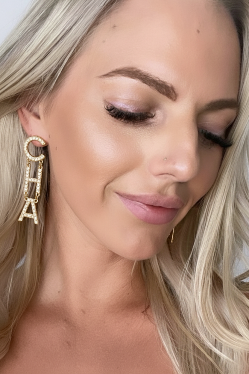 Close-up of a woman wearing gold earrings with 'A' charms.