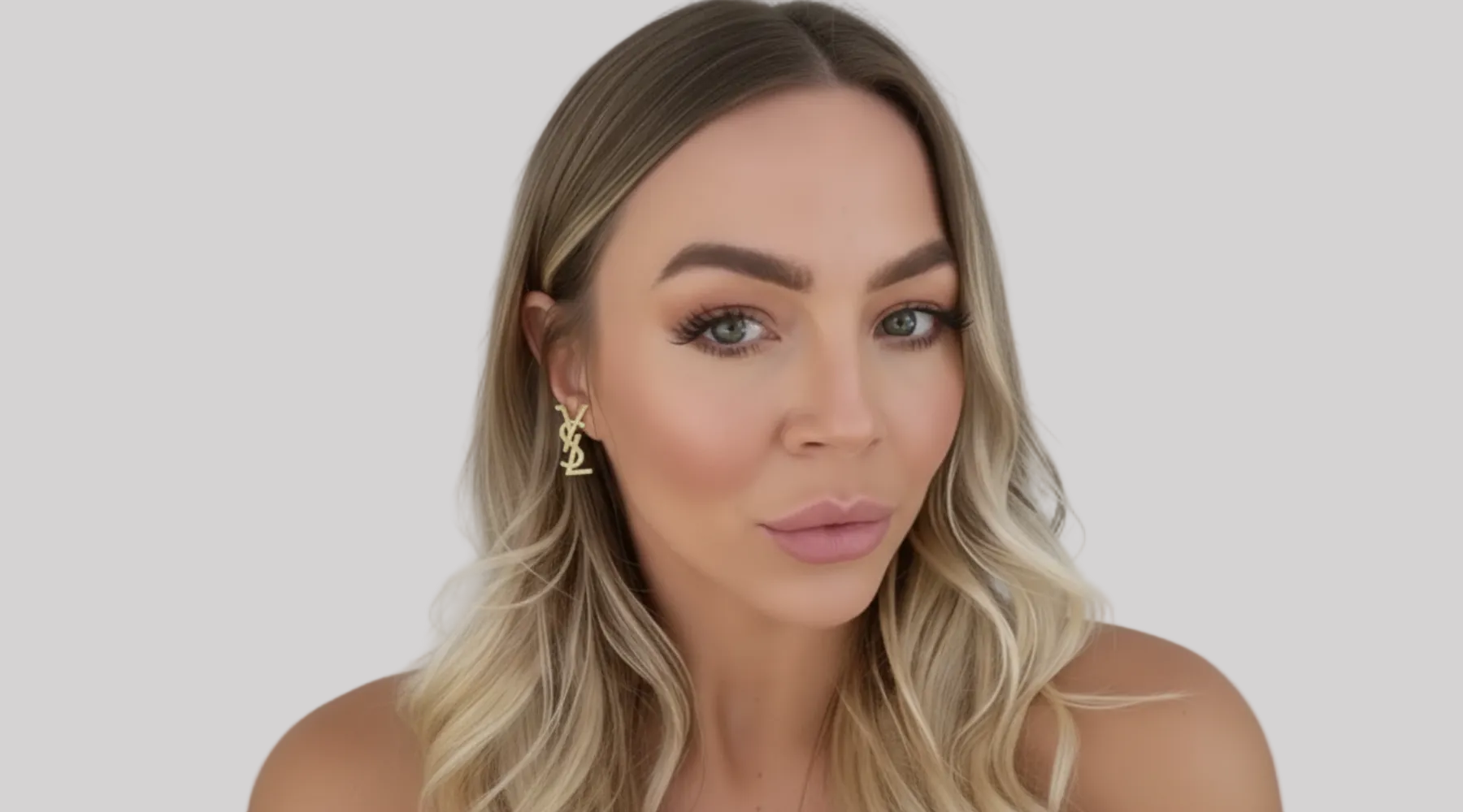 Woman wearing gold earrings against a plain background