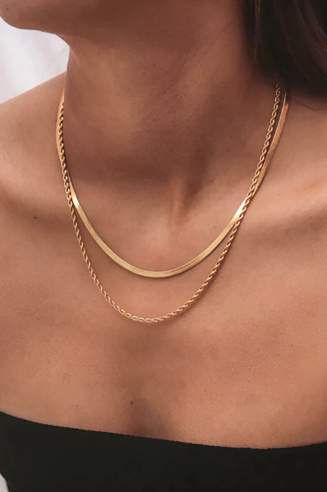 Gold chain necklace on a person's neck with a blurred background