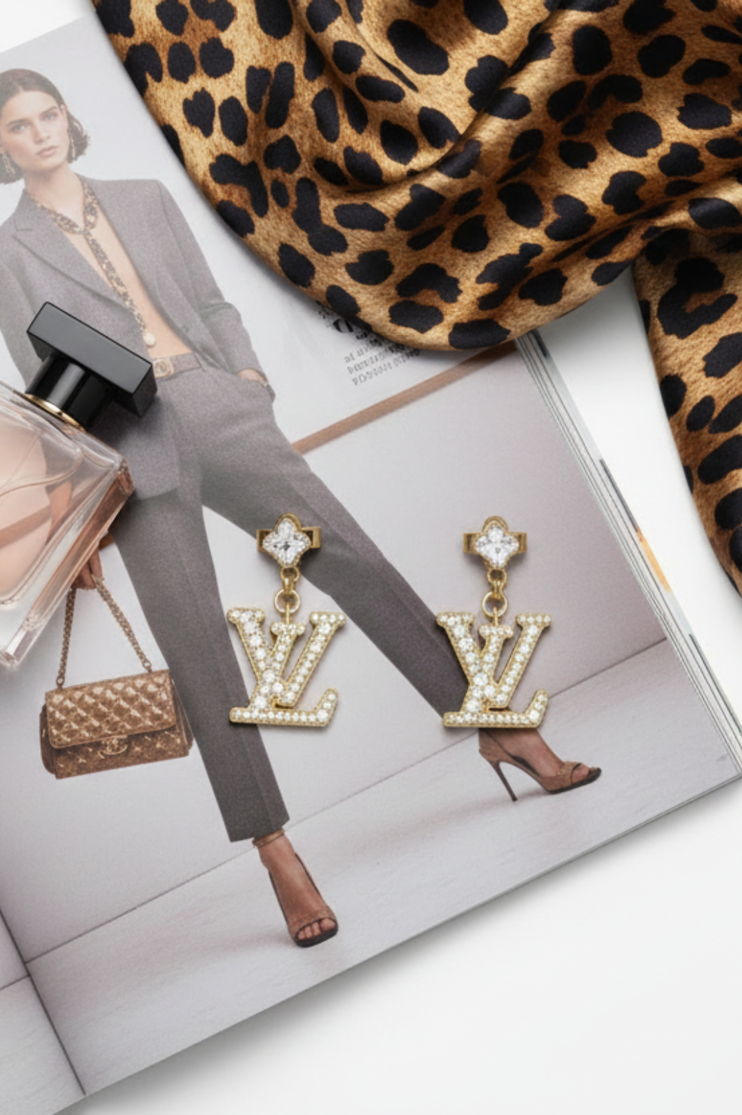 earrings displayed on a magazine with leopard print fabric and perfume bottle.