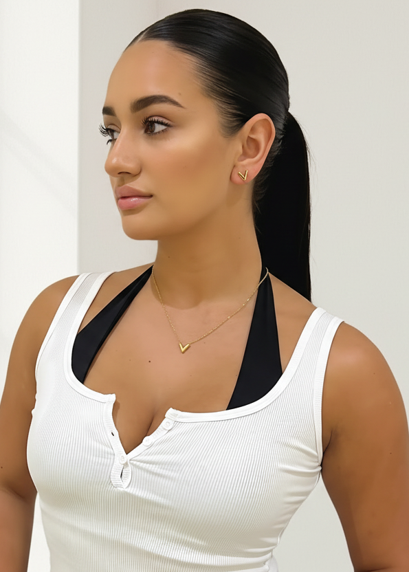 Woman wearing a white tank top with black trim against a light background