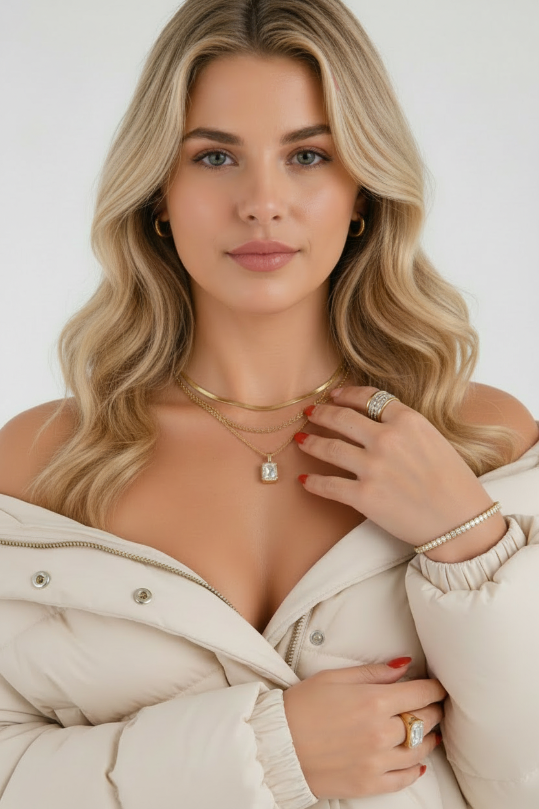 Woman wearing a beige puffer jacket with jewelry on a plain background